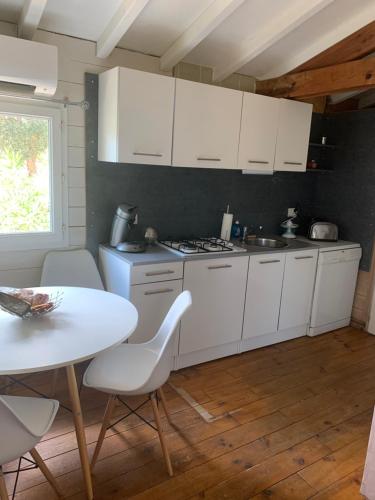 une cuisine avec des placards blancs et une table et des chaises blanches dans l'établissement La Petite Maison dans le Maquis, à Porto-Vecchio