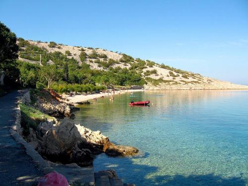a beach with a red boat in the water at Rooms with a parking space Lukovo, Senj - 14567 in Sveti Juraj