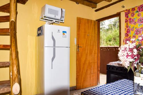 um frigorífico branco com uma televisão por cima em Mini Chalés Madeira Beach em Ubatuba