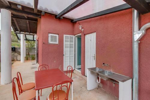 - un bâtiment rouge avec une table, des chaises et un lavabo dans l'établissement Apartments by the sea Nerezine, Losinj - 2516, à Nerezine