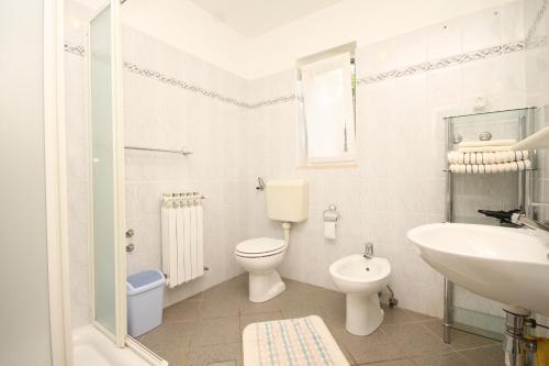 La salle de bains blanche est pourvue de toilettes et d'un lavabo. dans l'établissement Apartments with a parking space Nerezine, Losinj - 2518, à Nerezine