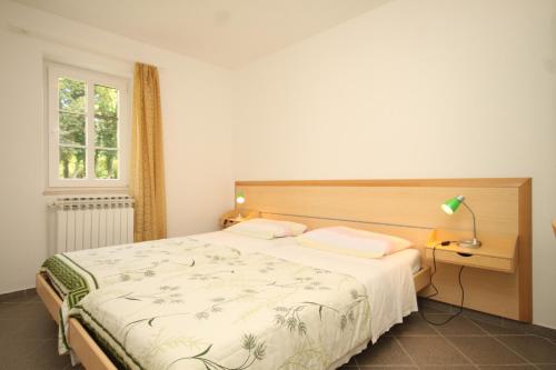 a bedroom with a bed and a lamp and a window at Apartments with parking space Nerezine, Losinj - 2518 in Nerezine
