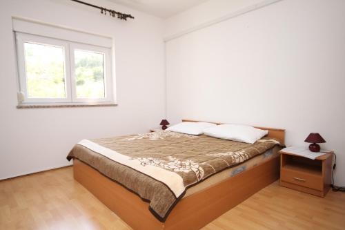 a white bedroom with a bed and a window at Apartment Metajna 527f in Metajna