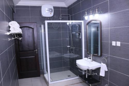 y baño con ducha, lavabo y espejo. en Lady M guest House, en Tema