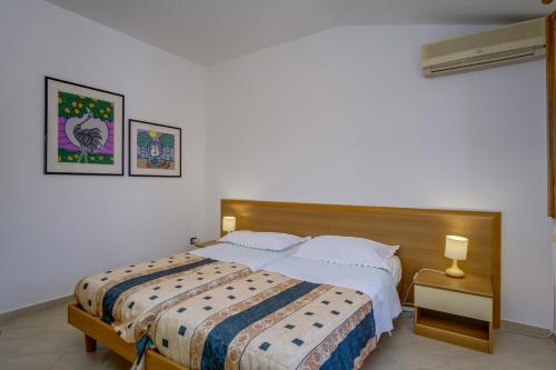 a bedroom with a large bed and a nightstand with a bed sidx sidx sidx at Apartments by the sea Nerezine, Losinj - 2519 in Nerezine