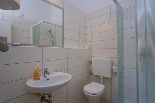 a bathroom with a sink and a toilet and a mirror at Apartments by the sea Nerezine, Losinj - 2519 in Nerezine