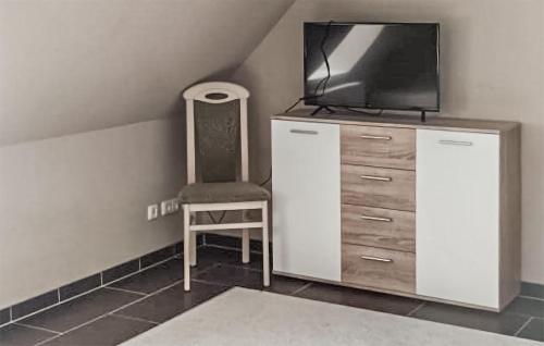 a room with a dresser with a tv and a chair at 2 Bedroom Cozy Apartment In Krakow Am See in Krakow am See