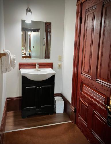 a bathroom with a white sink and a mirror at The Monarch Hotel in Port Townsend