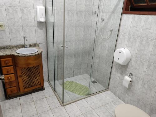 a bathroom with a shower with a sink and a toilet at Praia Virgem Hostel in Rio das Ostras