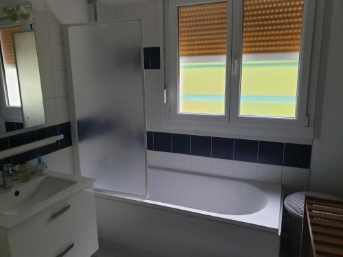 une salle de bain avec une baignoire, un lavabo et une fenêtre dans l'établissement Appartement, Verdun , proche centre ville, à Verdun-sur-Meuse