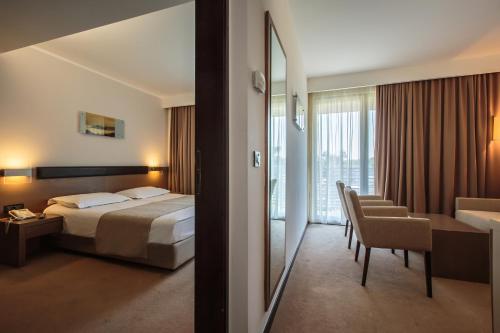 a hotel room with a bed and a desk and a mirror at Hotel Molindrio Plava Laguna in Poreč