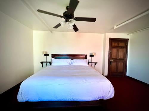 a bedroom with a white bed with a ceiling fan at The Monarch Hotel in Port Townsend