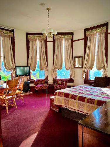 a bedroom with a bed and a table and chairs at The Monarch Hotel in Port Townsend