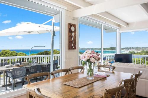 a dining room with a table with a vase of flowers at The Corner Cottage in Mollymook
