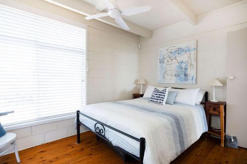 a bedroom with a bed and a ceiling fan at The Corner Cottage in Mollymook
