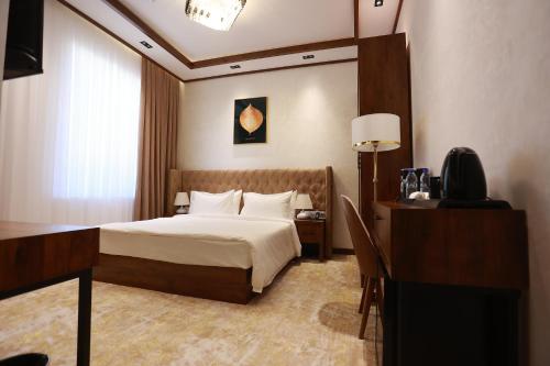 una habitación de hotel con una cama y un escritorio en Regal Hotel by Grand, en Navoi