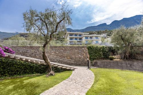 un albero seduto in un cortile accanto a un muro di pietra di Wellness Hotel Casa Barca (Adult Only) a Malcesine