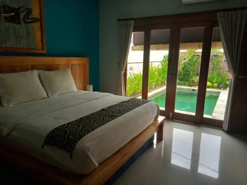 a bedroom with a bed and a window with a pool at Villa Triyuna, our little paradise in Banjar