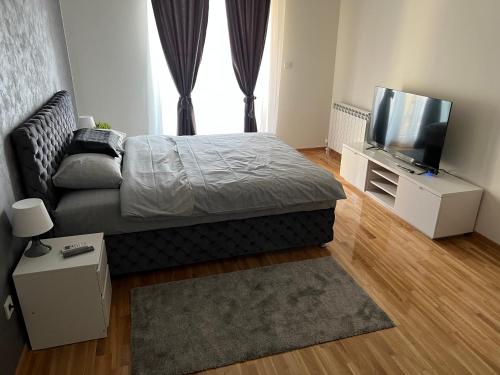 Schlafzimmer mit einem Bett und einem Flachbild-TV in der Unterkunft KoTa grey in Karaburma