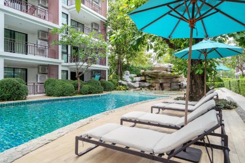 a pool with two lounge chairs and an umbrella at The Title Rawai Beach West Wing Pool Access Aparment in Rawai Beach