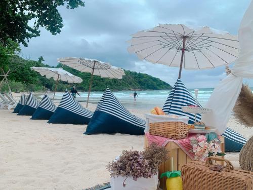 a row of blue and white umbrellas on a beach at Kerala Coco Resort in Ko Samed