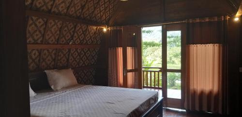 1 dormitorio con cama y ventana grande en Villa Lumbung Ayu Sari & Spa, en Karangasem