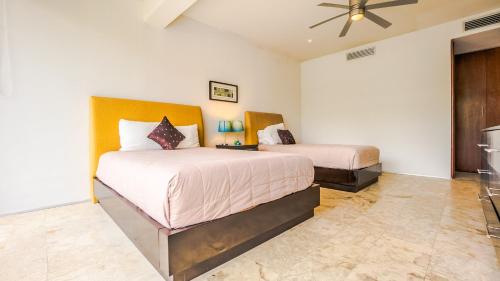 a bedroom with two beds and a ceiling fan at Magia Beachside Apartment by BVR in Playa del Carmen