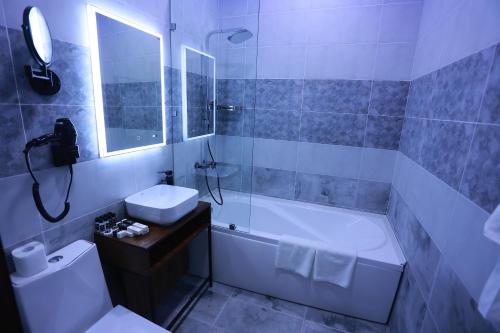 Un baño con bañera, inodoro y lavabo. en Regal Hotel by Grand, en Navoi