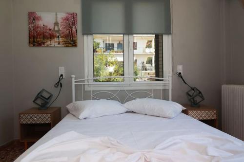 1 cama blanca con 2 almohadas y ventana en Beautiful apartment in Plomari, en Plomari