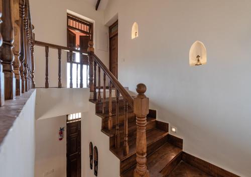a staircase in a home with white walls and wooden railings at SaffronStays Niramay, Torna-Rajgad - rustic pool villa with a gazebo and great forest views in Mārg Āsni