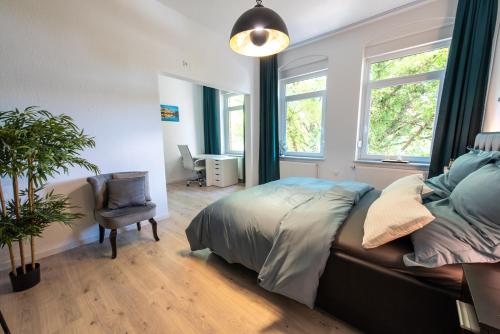 a bedroom with a bed and a chair and windows at 4-Zimmer Wohnung mit grandioser Aussicht in zentraler Lage in Hannover
