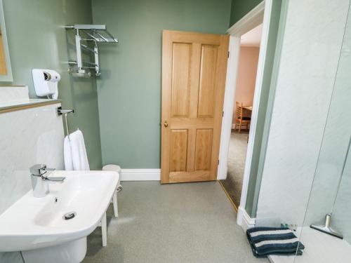 a bathroom with a sink and a wooden door at The Ticket Office Allerston in Pickering