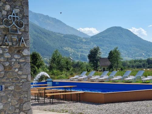 una piscina con sillas y montañas en el fondo en Hotel & Restaurant Ada en Gusinje