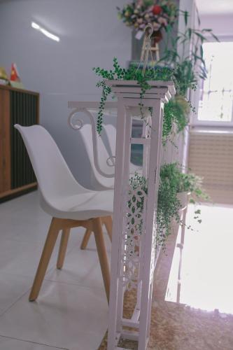 a white chair sitting next to a table with plants at Vagibi Hotel in Dong Hoi