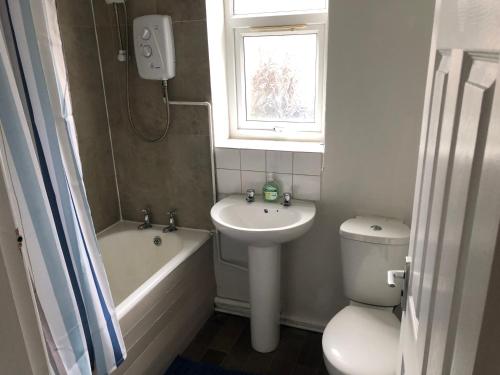 a bathroom with a sink and a toilet and a window at 4-Bedroom House Close to Barnsley Centre in Barnsley