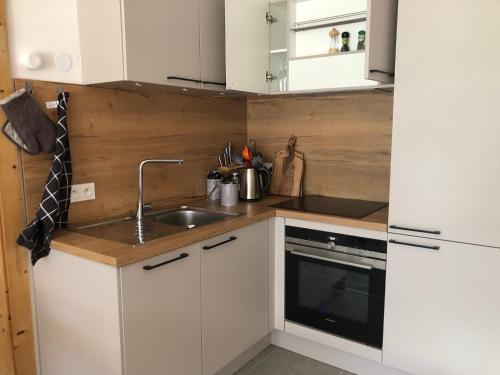 une petite cuisine avec des armoires blanches et un évier dans l'établissement Apartment A304 La Perle de Savoie, à Châtel