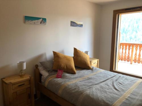 1 dormitorio con cama con almohadas y ventana en Apartment A304 La Perle de Savoie, en Châtel
