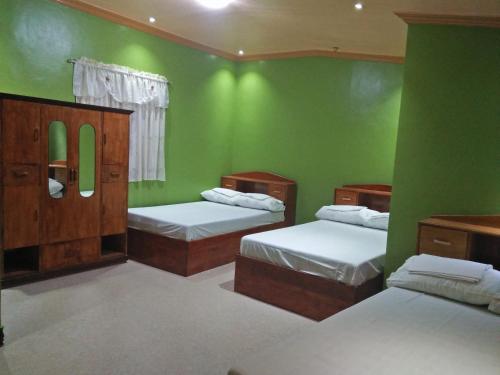 a room with three beds and green walls at Villa Corrales Homestay in Mambajao