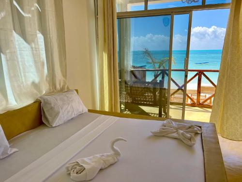 a bedroom with a bed with a view of the ocean at Equalia Rose hotel in Jambiani