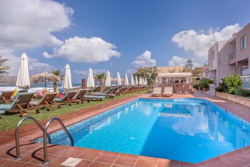 una piscina con tumbonas junto a un complejo en Solimar Turquoise - Adults Only en Agia Marina Nea Kydonias