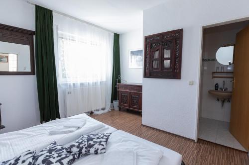 a bedroom with a bed and a bathroom with a sink at Ringhaus - Home of Silver Arrows in Nürburg