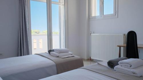 deux lits dans une chambre avec une grande fenêtre dans l'établissement Villa Sophie, à La Canée