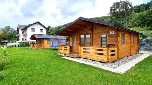 a log cabin in a yard with a house at Domki Na Stoku Laworty in Ustrzyki Dolne