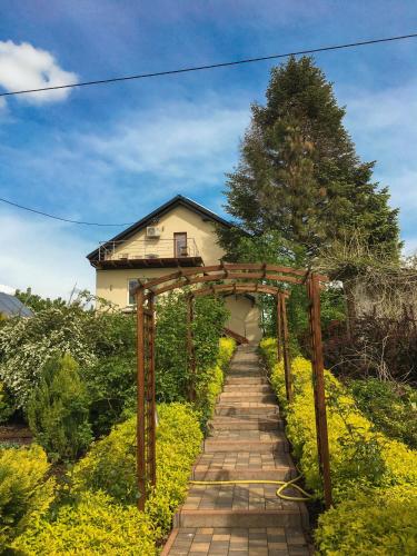 a brick pathway leading to a house with a wooden arch at Pensjonat Nad Strumykiem in Sandomierz