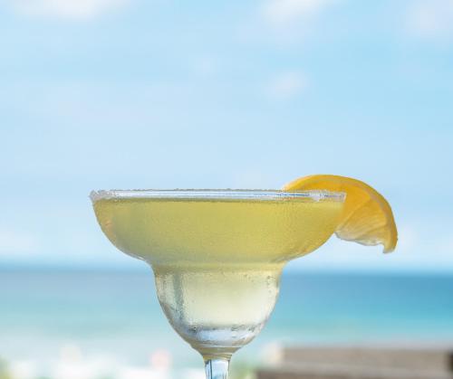 una bebida amarilla con una rodaja de naranja en la parte superior en The Palms Resort & Bar, en San Narciso