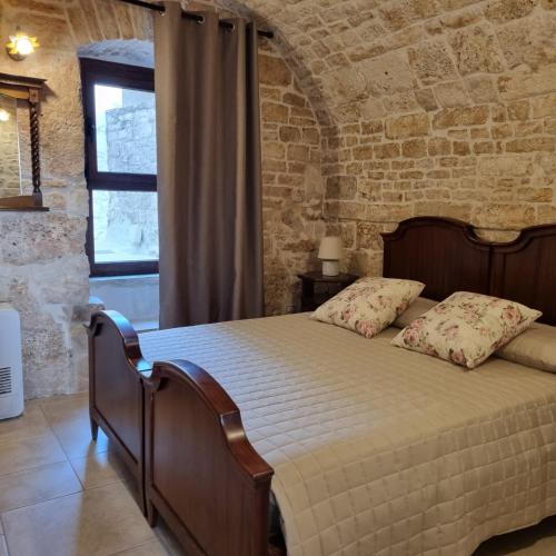 um quarto com uma cama numa parede de tijolos em La tana degli Incerti em Alberobello