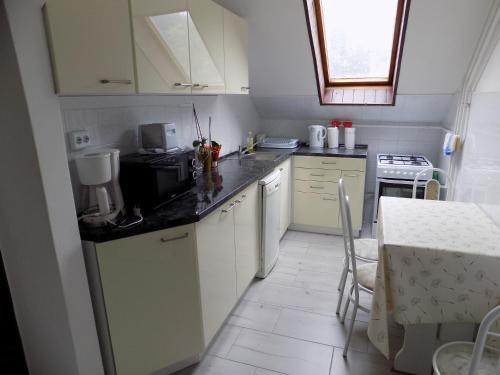 a small kitchen with white cabinets and a table and a window at Charlie Vendégház,emelet 8 fős,100m2-es apartman in Siófok