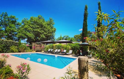 a swimming pool with chairs and umbrellas in a yard at Le Gîte du Diamant Noir in Aups