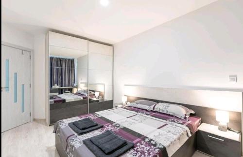 a bedroom with a large bed and a large mirror at Moderna Apartment in Burgas City