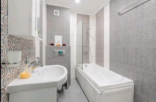 a bathroom with a sink and a tub and a toilet at Moderna Apartment in Burgas City